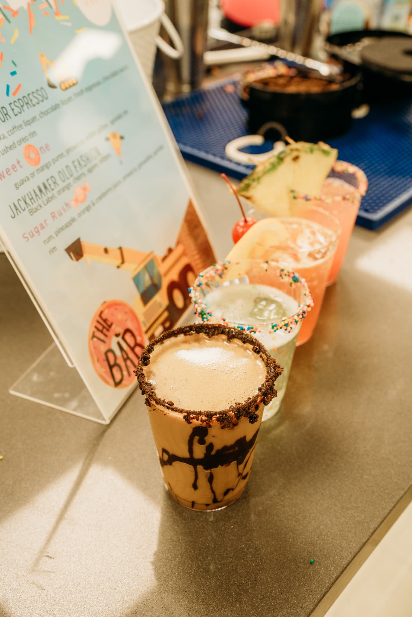 A lineup of dessert cocktails with chocolate-drizzled rims beside a printed bar menu