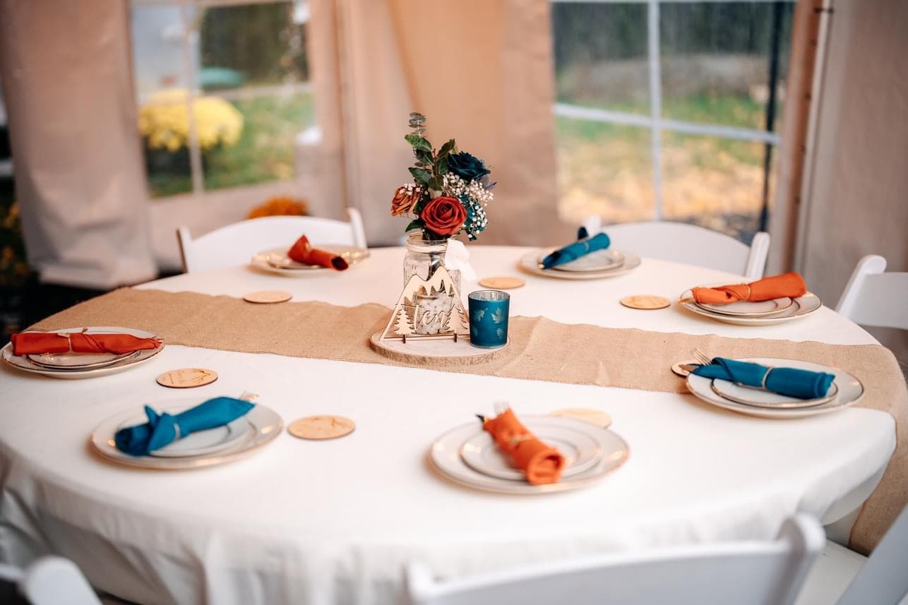 A round table with a white cloth, colorful napkins, and a floral centerpiece